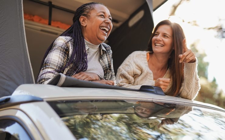 Happy multiracial polygamy senior women having fun during travel vacation inside mini van camper - Elderly female friendship and healthy lifestyle concept