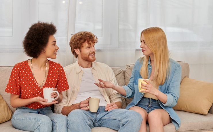 polyamorous family, relationship diversity, cheerful polygamy lovers sitting on couch and chatting